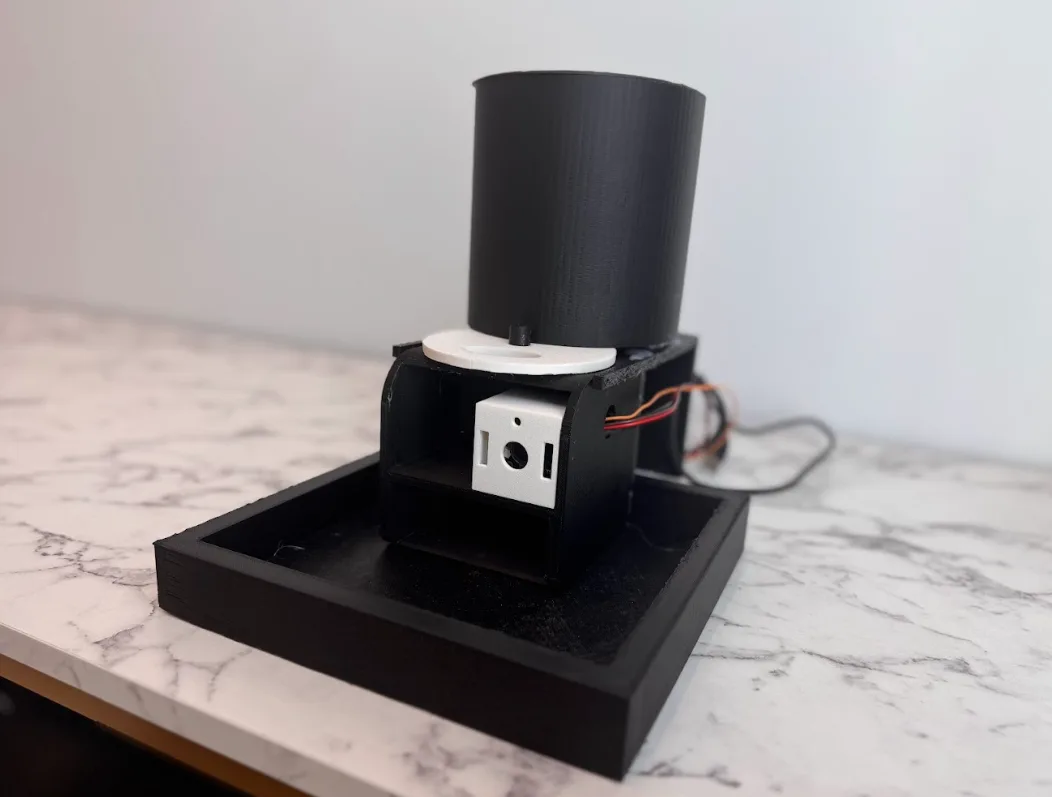 The Ornimetrics feeder: black seed hopper on a camera housing over a square tray